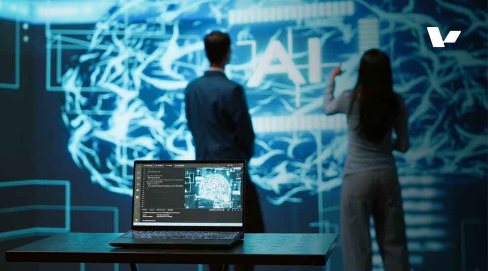 A futuristic workspace featuring a laptop displaying AI-generated data, with two professionals analyzing a large digital twin projection in the background.
