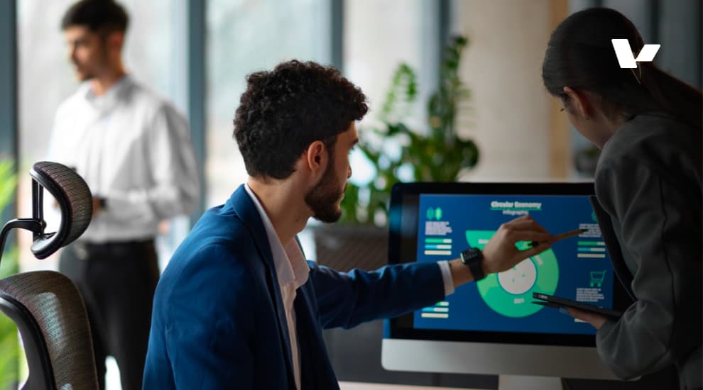 A business team discussing data analytics and infographics on a computer screen, showcasing a collaborative work environment with a focus on technology and innovation.