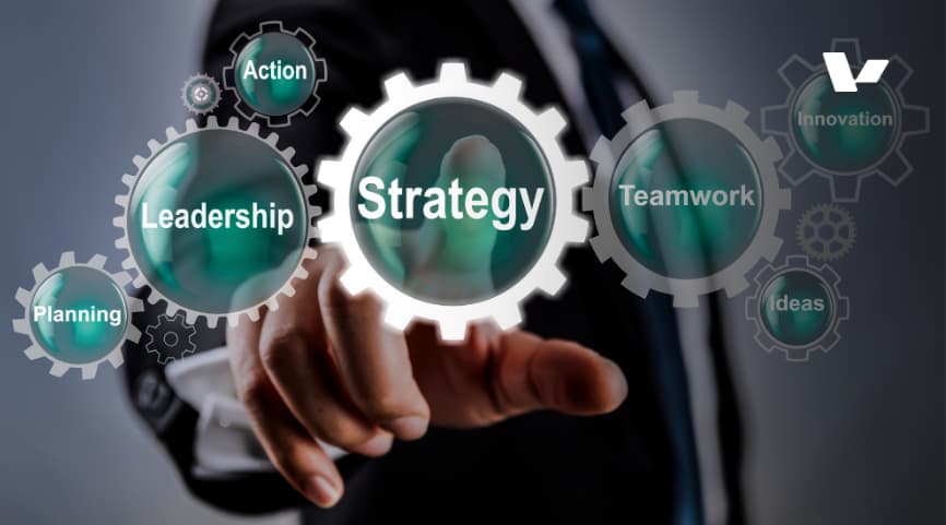 A business professional pointing towards gears with words like "Strategy," "Leadership," "Action," "Planning," "Teamwork," "Innovation," and "Ideas" displayed inside