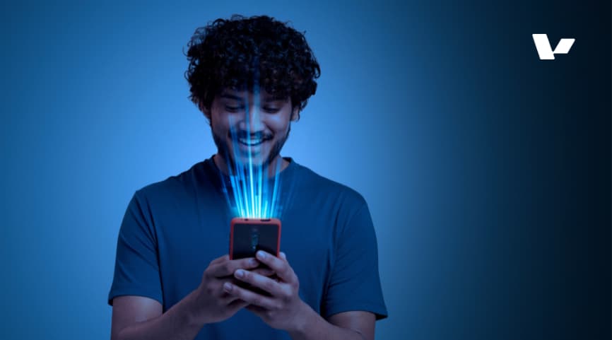 A young man smiling and interacting with a smartphone, with digital light rays emanating from the phone